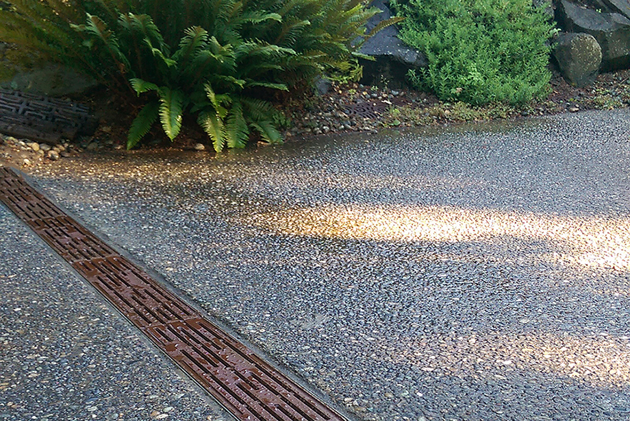 Decorative outdoor drain grate blending into a landscaped backyard